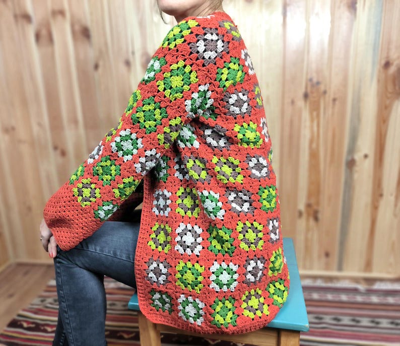 May include: A crocheted cardigan with a granny square pattern in shades of orange, green, white, and brown.