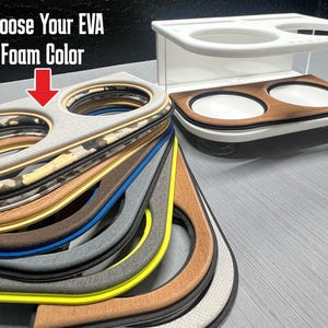 May include: A display of EVA foam cup holder inserts in various colors, including camouflage, brown, blue, and yellow. The text "Choose Your EVA Foam Color" is at the top. A white cup holder is also shown.