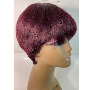 May include: A short, burgundy wig with a blunt cut and bangs. The wig is styled on a mannequin head.
