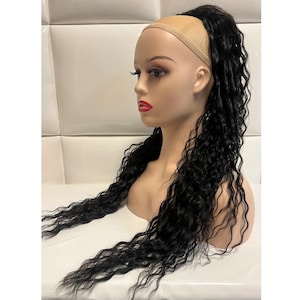 May include: A black curly hair extension with a brown hairpiece attached to the top. The hair extension is long and wavy.