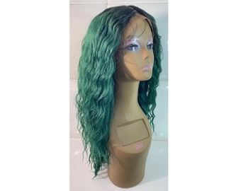 May include: A long, wavy, emerald green wig displayed on a mannequin head. The wig features a lace front and a natural-looking hairline. The hair is styled with loose, voluminous waves, creating a full and textured appearance.