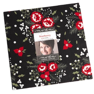 May include: A black fabric square with a floral pattern featuring red flowers, white accents, and green leaves. The fabric has a tag that reads "Starberry" and "moda FABRICS + SUPPLIES".