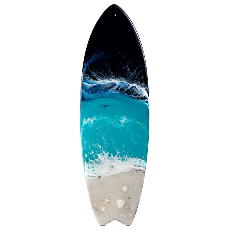 May include: A surfboard with a resin art design depicting a beach scene with blue water, white waves, and a sandy shore with seashells. The surfboard is black at the top and fades to a light gray at the bottom.