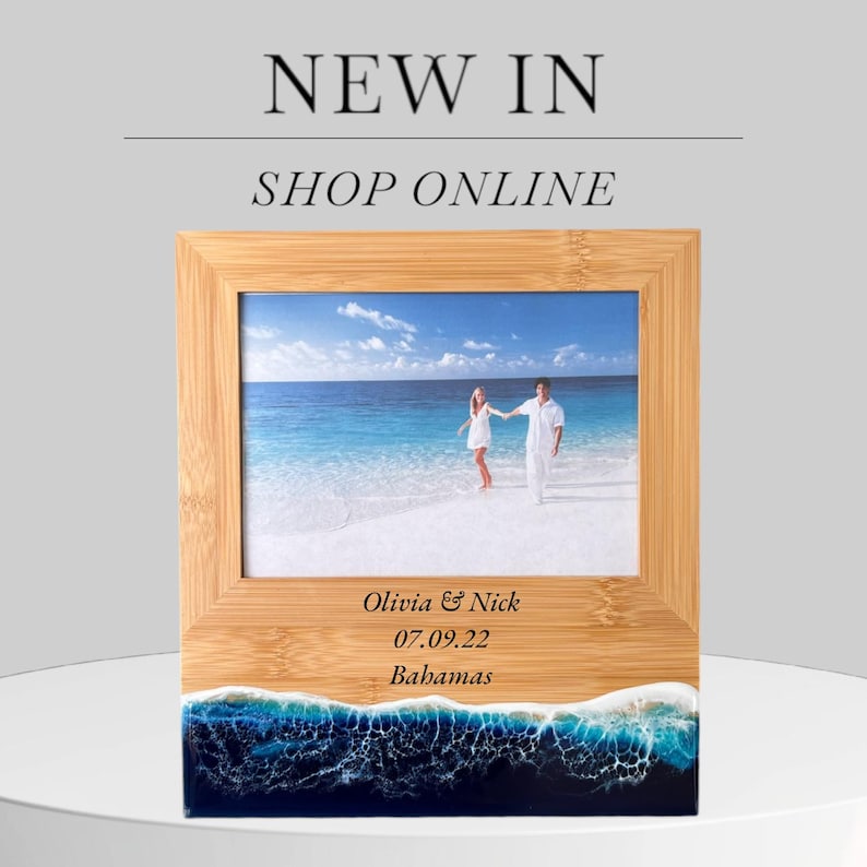 May include: A wooden photo frame with a beach scene photo and a personalized inscription. The inscription reads "Olivia & Nick 07.09.22 Bahamas". The frame has a blue and white resin base that resembles ocean waves.