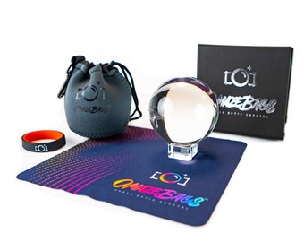 May include: A clear glass crystal ball on a stand, with a black pouch, a black box with the text "[O]maze Balls" and a black and rainbow patterned mat with the text "[O]maze Balls".