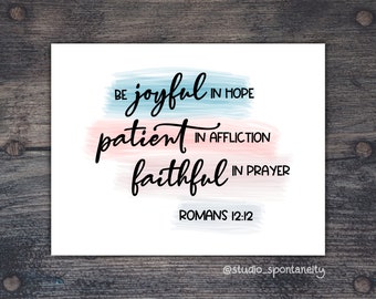 May include: A white printable art print with a blue and pink watercolor background. The text reads "Be joyful in hope, patient in affliction, faithful in prayer, Romans 12:12".