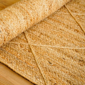 May include: A natural fiber rug with a diamond pattern woven into the design. The rug is made of jute and has a natural beige color.