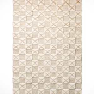 May include: A beige and white woven rug with a geometric pattern. The rug has a fringe border.