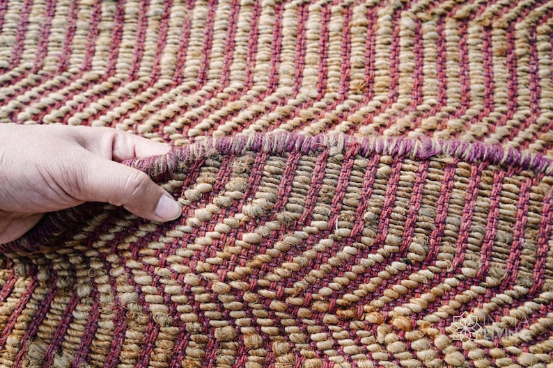 May include: Close-up of a woven rug with a chevron pattern in shades of brown and pink.