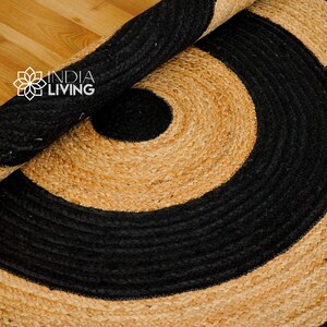 May include: A round jute rug with a black and natural color pattern. The rug has a concentric circle design with a black outer ring and a natural inner ring.