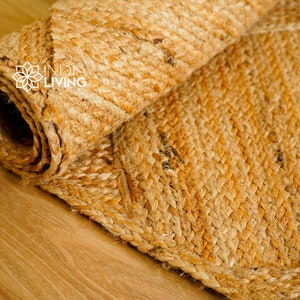 May include: A close-up of a natural fiber rug made from woven jute. The rug is rolled up and has a natural, earthy color.