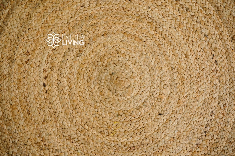 May include: Close-up of a natural woven rug with a circular pattern. The rug is made of a light brown material and has a textured surface.
