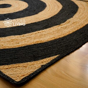 May include: A round jute rug with black and natural colored stripes in a concentric circle pattern. The rug is made of natural fibers and has a rustic look.
