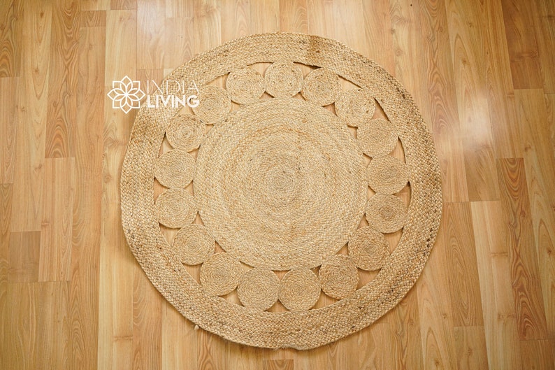May include: A round, natural fiber rug with a woven design of circles. The rug is made of jute and has a natural, earthy color.