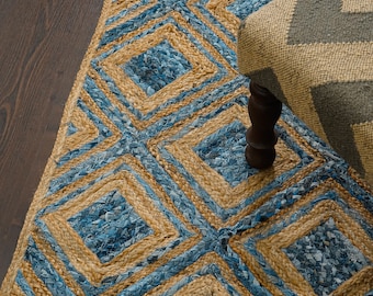 Puede incluir: Una alfombra tejida azul y marrón con un patrón geométrico. La alfombra está hecha de yute y mezclilla.