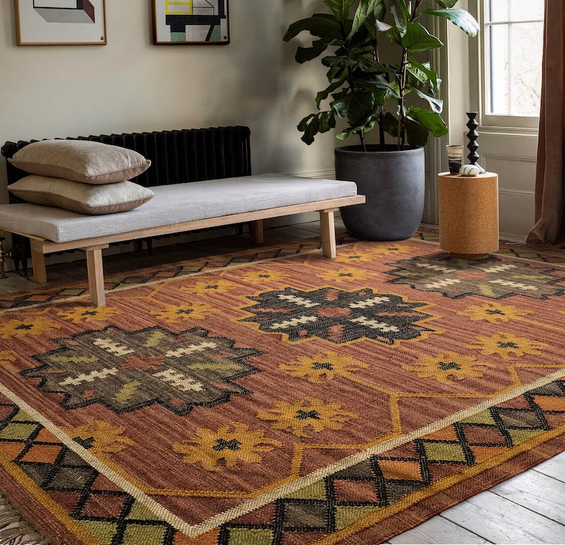 May include: A brown and orange patterned rug with a geometric design. The rug has a dark brown center with a lighter brown border. The rug is on a wooden floor.