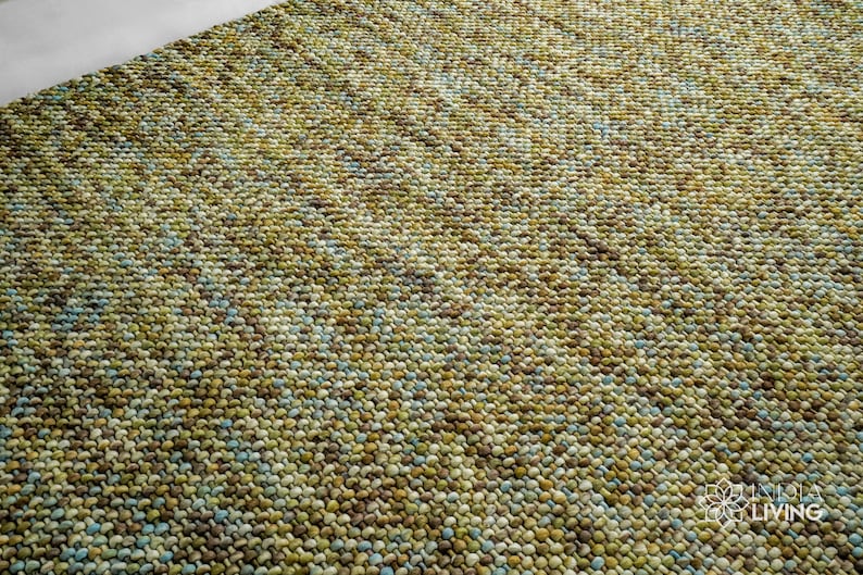 May include: Close-up of a green, blue, and brown textured rug. The rug is made of small, round, woven balls of yarn.