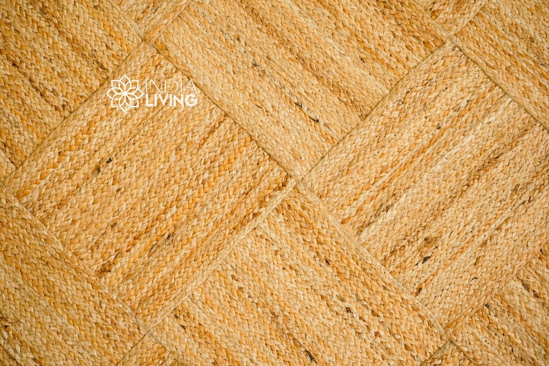 May include: A close-up of a natural fiber woven rug with a diamond pattern. The rug is a light brown color and has a textured surface.