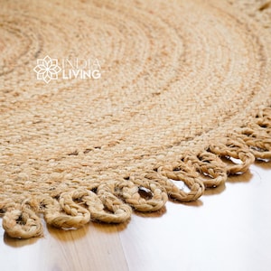 May include: A round jute rug with a braided fringe border. The rug is made from natural fibres and has a light brown colour.