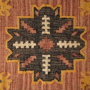 May include: A close-up of a brown, black, and cream patterned rug with a geometric design. The rug has a woven texture and a traditional style.