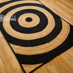 May include: A black and natural jute rug with a large concentric circle pattern. The rug has a modern, geometric design.