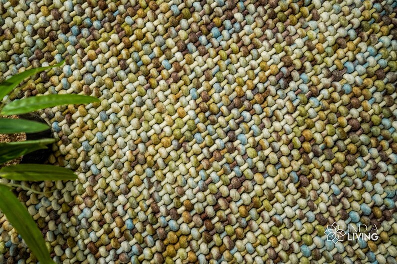 May include: Close-up of a woven rug with a textured surface. The rug is made of a variety of colors, including brown, beige, green, and blue.