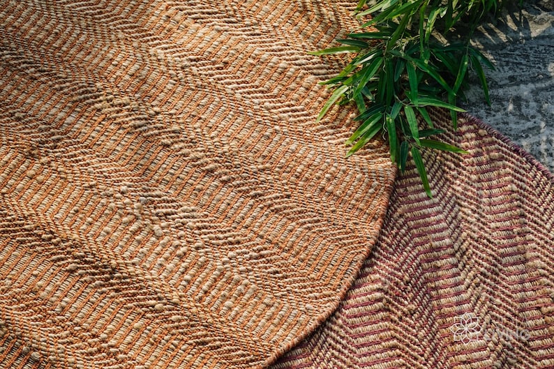 May include: Two woven rugs with a chevron pattern. The rug on the left is a light brown and cream color. The rug on the right is a darker brown and cream color with a hint of pink.
