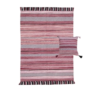 May include: A woven rug and matching pillow set in shades of pink, gray, and white. The rug features horizontal stripes and geometric patterns, with fringe detailing on the edges. The pillow has a similar striped design and tassels.