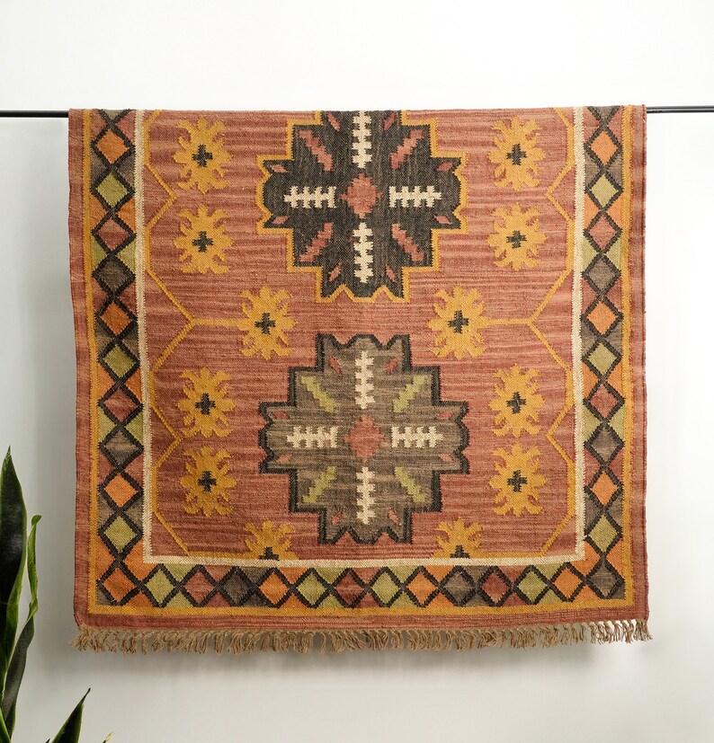 May include: A rectangular rug with a geometric pattern in shades of brown, orange, and yellow. The rug has a fringe border.
