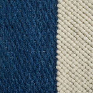 May include: Close-up of a woven rug with a blue and white striped pattern. The rug is made of thick, textured yarn.