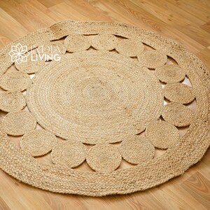 May include: A round, natural fiber rug with a woven design of circles around the outer edge. The rug is made of jute and has a natural, earthy color.