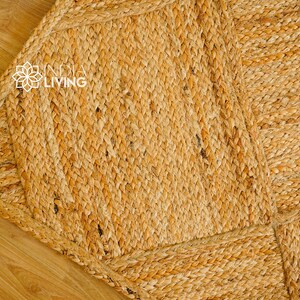 May include: A close-up of a natural fiber rug with a woven pattern. The rug is made of jute and has a light brown color.