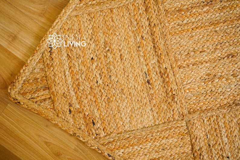May include: A close-up of a natural fiber rug with a woven pattern. The rug is made of jute and has a light brown color.