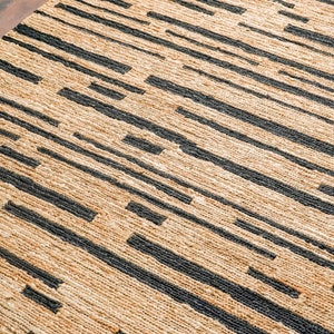 May include: A natural fiber rug with a woven pattern of black stripes on a beige background.