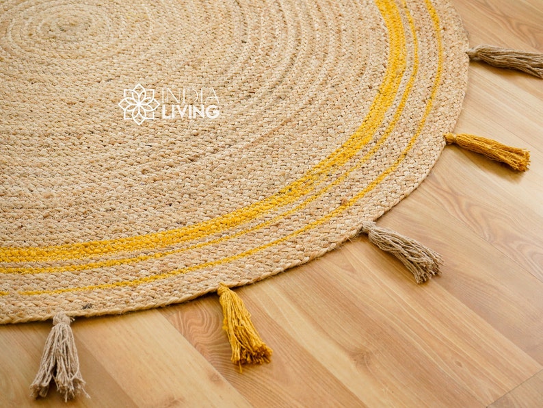 May include: A round jute rug with yellow stripes and tassels. The rug has a natural, earthy look and is perfect for adding a touch of bohemian style to any room.