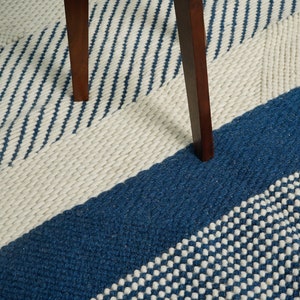 May include: A blue and white striped rug with a textured pattern. The rug is made of wool and has a modern design.