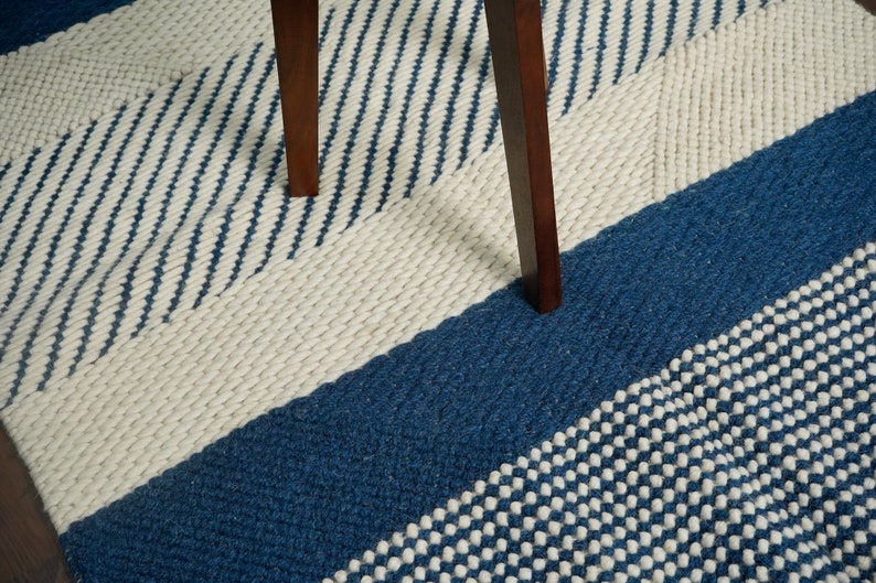 May include: A blue and white striped rug with a textured pattern. The rug is made of wool and has a modern design.