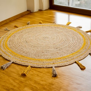 May include: A round jute rug with a yellow border and fringe. The rug has a natural, woven texture and is perfect for adding a touch of warmth and bohemian style to any room.