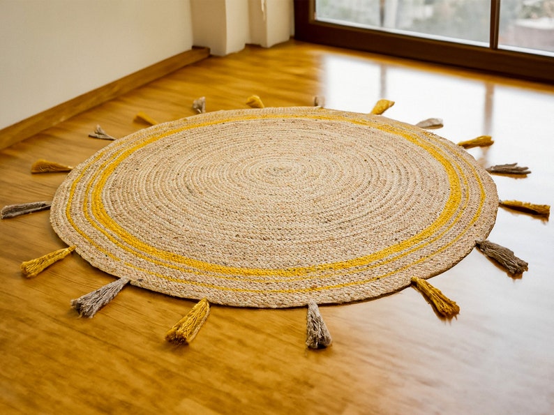 May include: A round jute rug with a yellow border and fringe. The rug has a natural, woven texture and is perfect for adding a touch of warmth and bohemian style to any room.