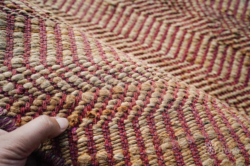 May include: Close-up of a woven rug with a chevron pattern in shades of brown and pink.