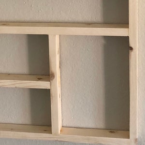 May include: A natural wood shelf unit with three shelves. The shelves are unfinished and have a light wood color. The text "Natural (No Stain)" is printed below the shelves.
