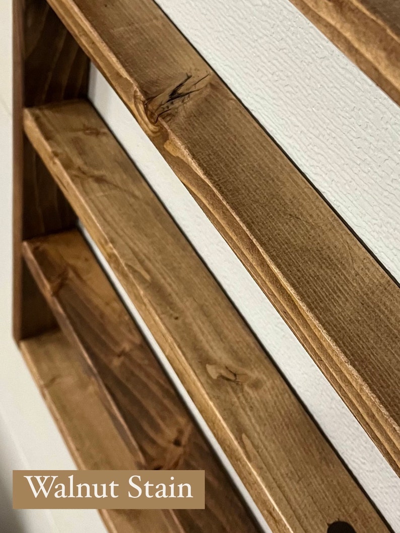 May include: A wooden shelf unit with three shelves stained in a walnut color. The shelves are angled and the wood grain is visible. The text "Walnut Stain" is visible at the bottom of the image.