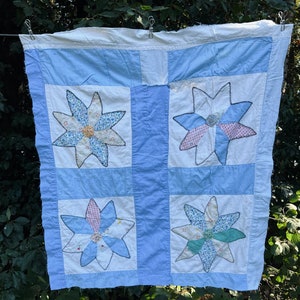 May include: A blue and white patchwork quilt with a starburst pattern. The quilt is made of different fabrics and has a vintage look.