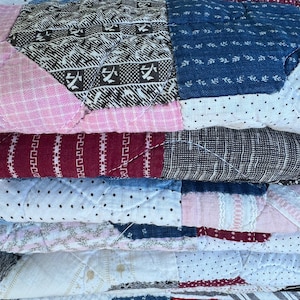 May include: A stack of fabric squares in various colors and patterns, including red, blue, white, and pink. The fabric is quilted and has a vintage look.