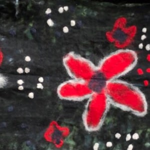 May include: A black fabric scarf with a white background and red flower designs. The flowers are painted on the fabric and have white outlines.