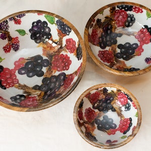 May include: Set of three wooden bowls with a white background and a black and red berry design.