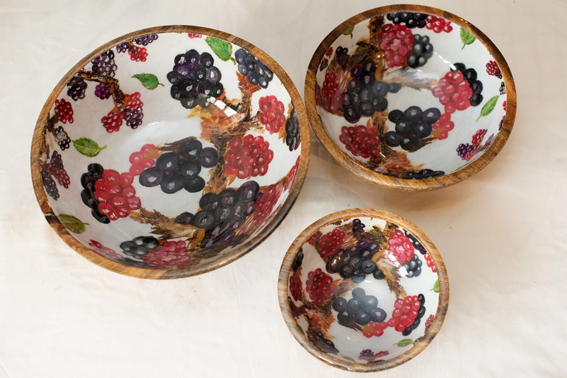 May include: Set of three wooden bowls with a white background and a black and red berry design.
