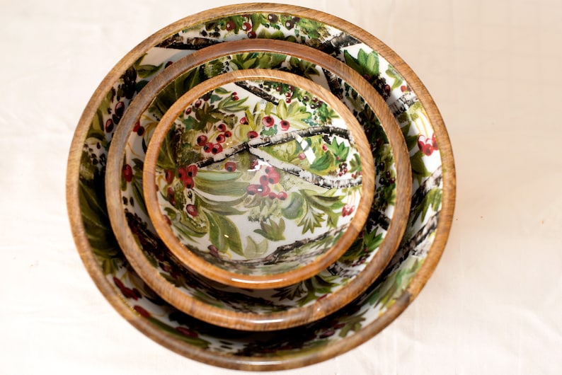 May include: Set of three nesting bowls with a white background and a floral pattern featuring green leaves, white branches, and red berries.