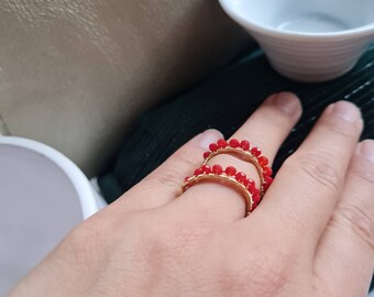 May include: Two gold rings with red beads. The rings are stacked on top of each other.