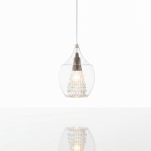 May include: Clear glass pendant light with a teardrop-shaped shade. The light fixture has a textured glass exterior and a decorative interior element. The light hangs from a thin white cord, creating a modern and elegant aesthetic.
